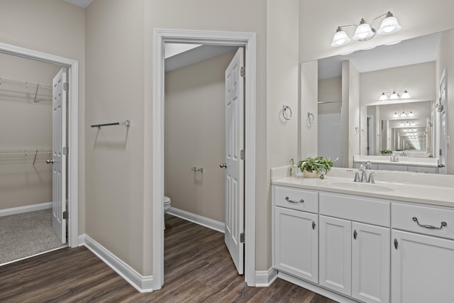 bathroom featuring wood finished floors, baseboards, toilet, and vanity