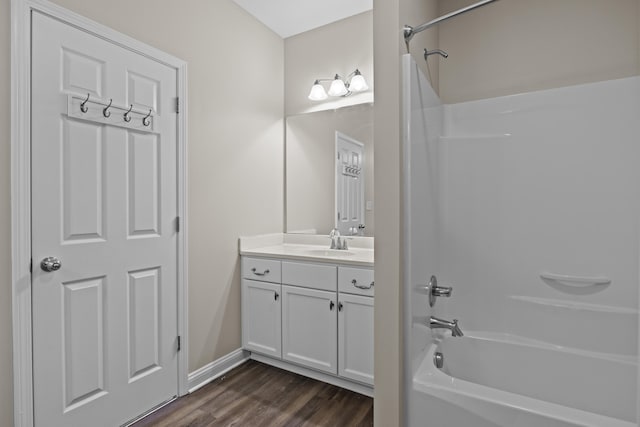 full bathroom with  shower combination, wood finished floors, vanity, and baseboards