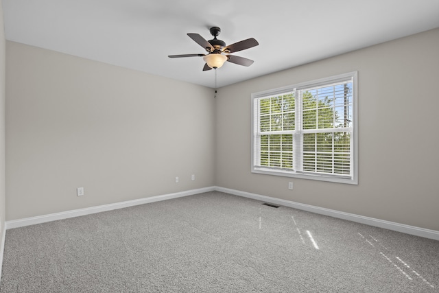 carpeted spare room featuring baseboards and a ceiling fan