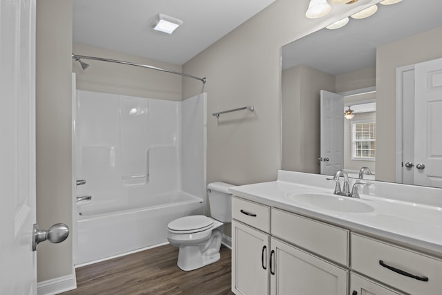 full bath featuring toilet, wood finished floors, vanity, washtub / shower combination, and baseboards