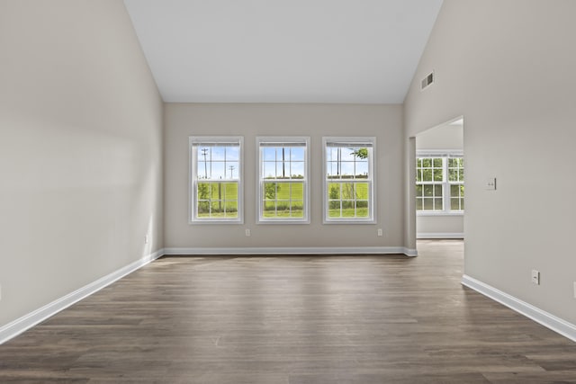 empty room with high vaulted ceiling, baseboards, and dark wood finished floors