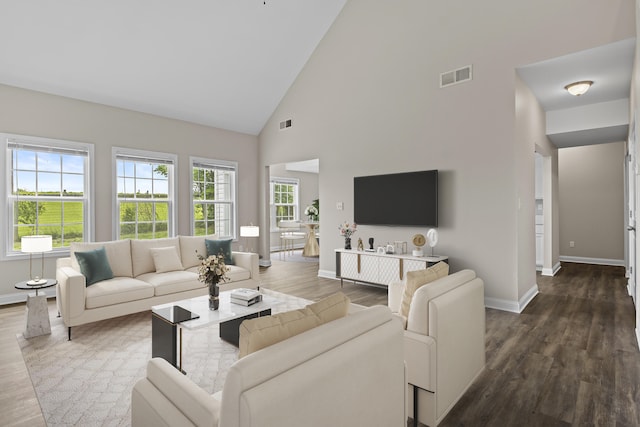 living area with high vaulted ceiling, baseboards, and dark wood-type flooring