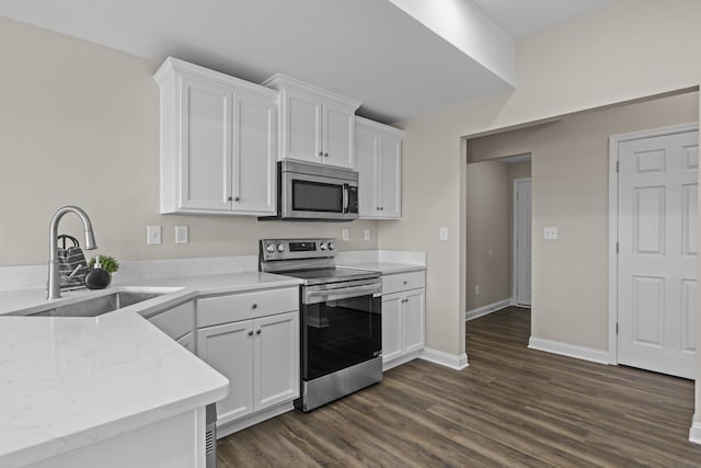 kitchen with appliances with stainless steel finishes, a sink, white cabinets, and dark wood-style floors