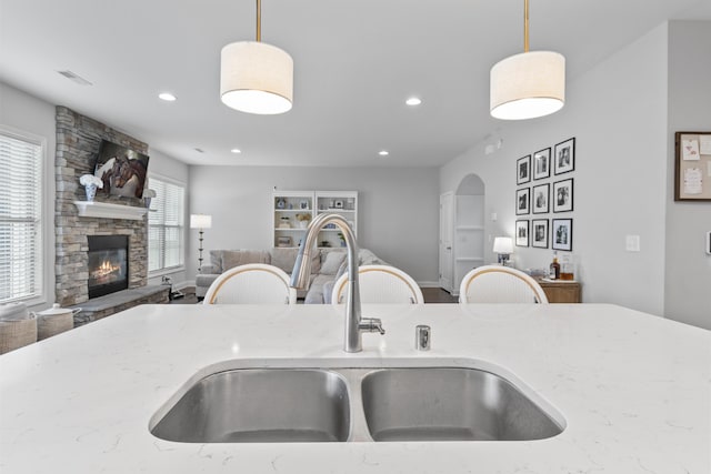 468 Lucille Dr, Lexington, KY 40511 - kitchen with open floor plan, a sink, light stone countertops, decorative light fixtures, and a fireplace