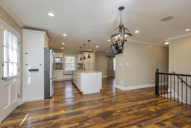 kitchen with appliances with stainless steel finishes, ornamental molding, recessed lighting, a chandelier, and a kitchen island with sink