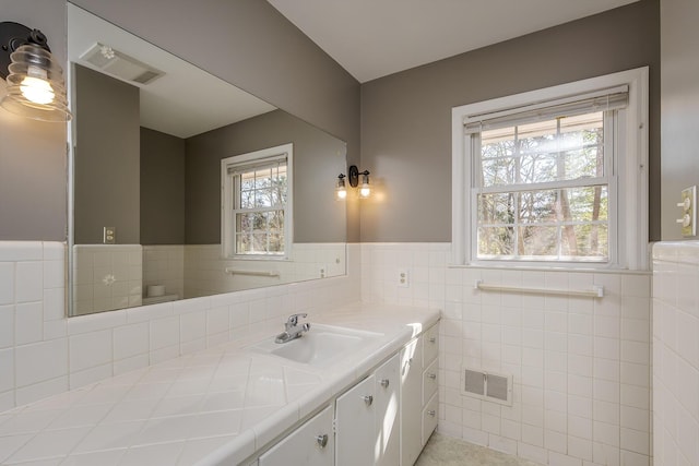 bathroom with tile walls, a wainscoted wall, and vanity