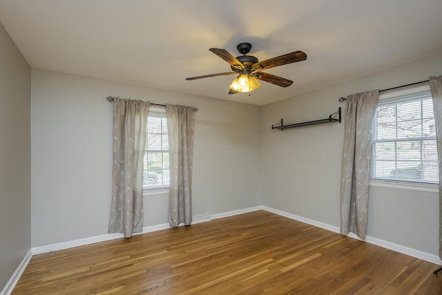 empty room with wood finished floors, baseboards, and a ceiling fan