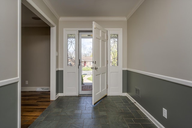 foyer featuring stone tile floors, healthy amount of natural light, ornamental molding, and baseboards