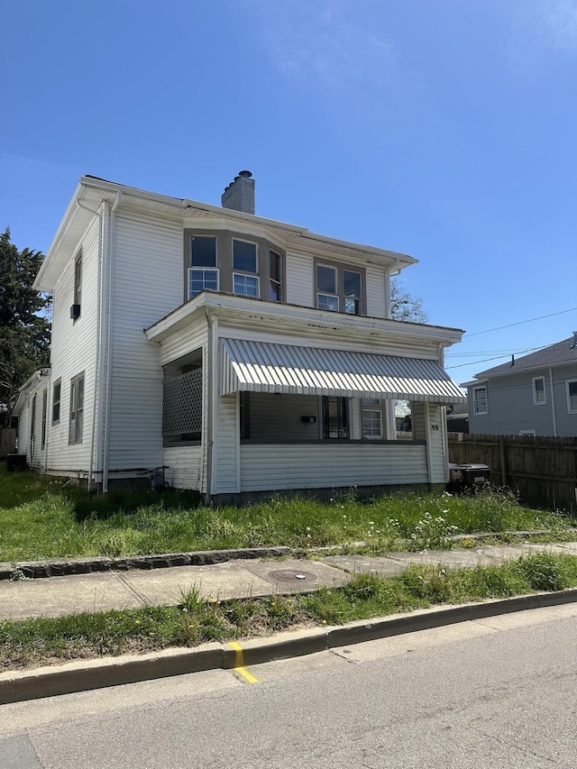 view of front of house with a chimney and fence