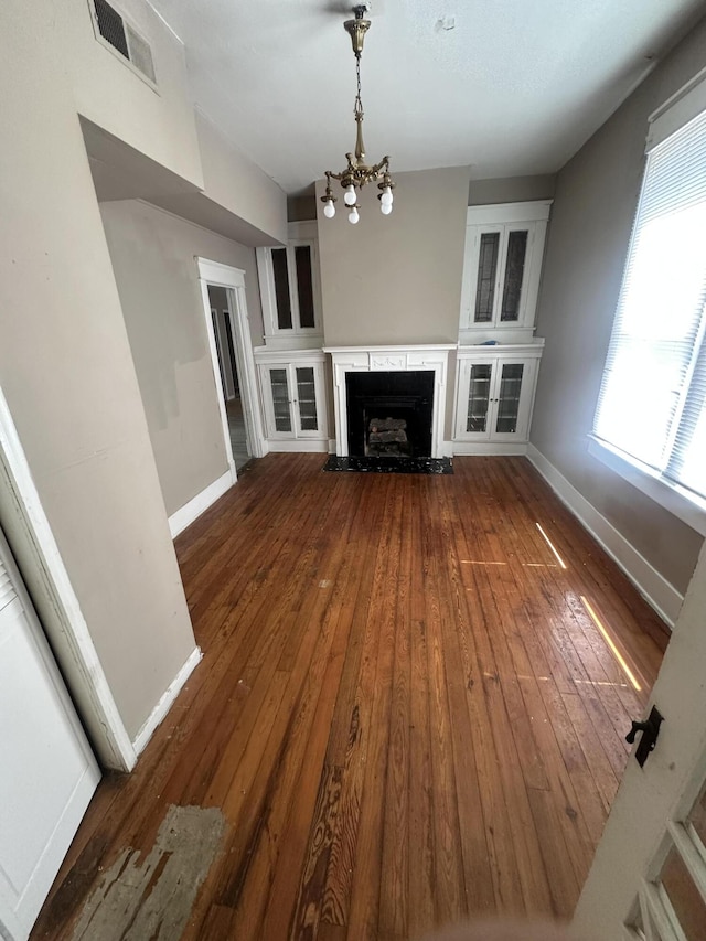 unfurnished living room featuring a chandelier, hardwood / wood-style flooring, baseboards, and a high end fireplace