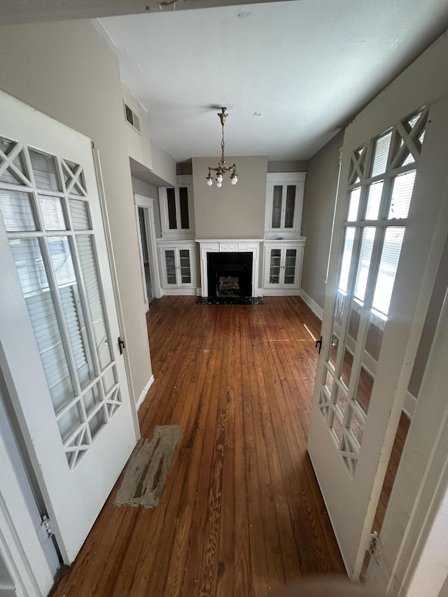 unfurnished living room with a chandelier, dark wood-style flooring, baseboards, and a premium fireplace