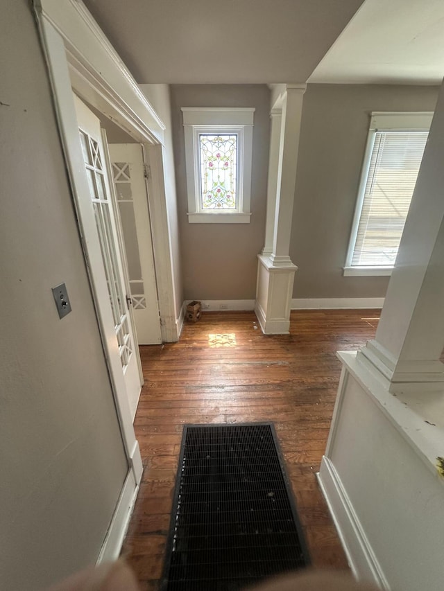 hall featuring ornate columns, hardwood / wood-style floors, and baseboards