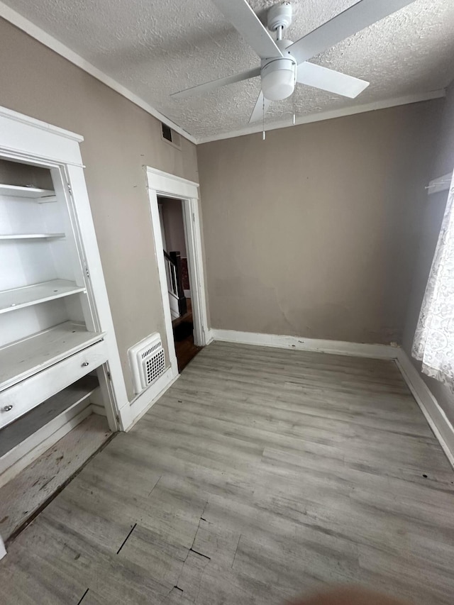 unfurnished room with a textured ceiling, ceiling fan, wood finished floors, and baseboards