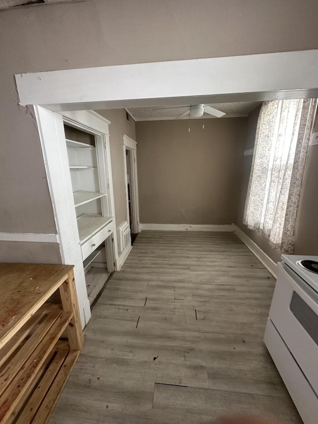 unfurnished dining area with ceiling fan, wood finished floors, and baseboards