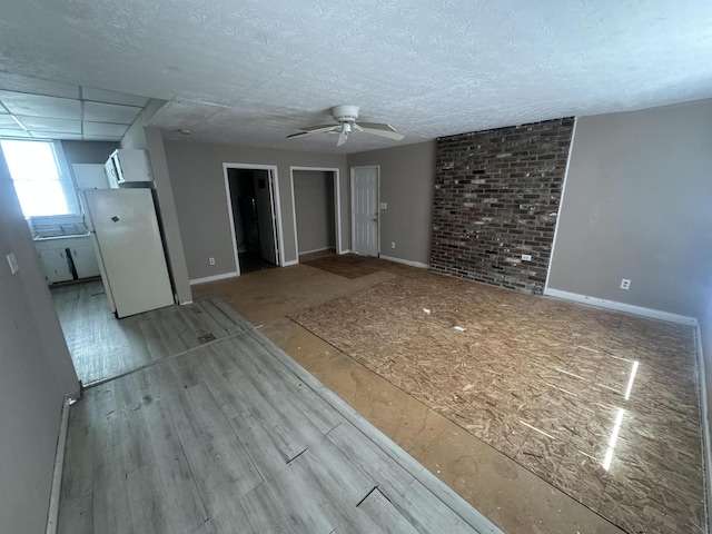 unfurnished living room featuring a ceiling fan, baseboards, wood finished floors, and a textured ceiling