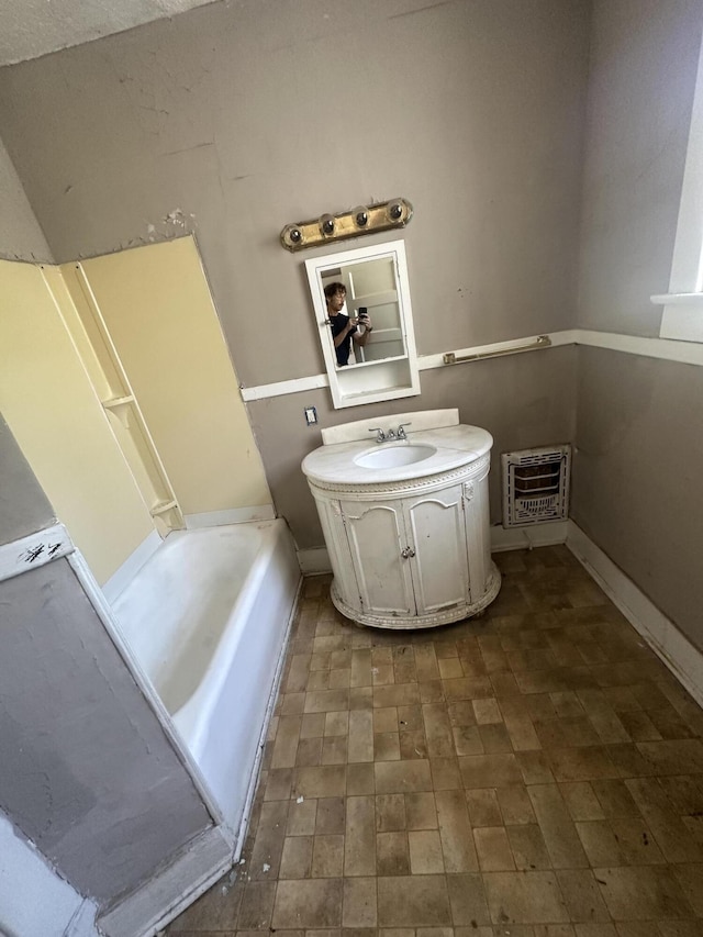 full bathroom with vanity, heating unit, a bathtub, and baseboards
