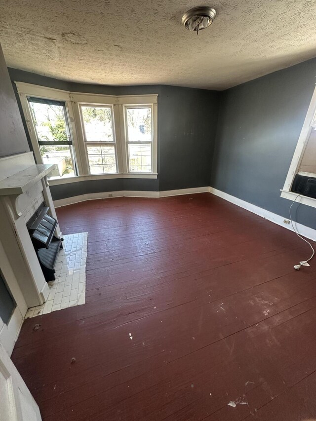 unfurnished living room featuring baseboards, a textured ceiling, hardwood / wood-style flooring, and cooling unit