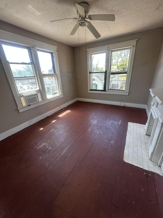 unfurnished room featuring hardwood / wood-style floors, a textured ceiling, baseboards, and plenty of natural light