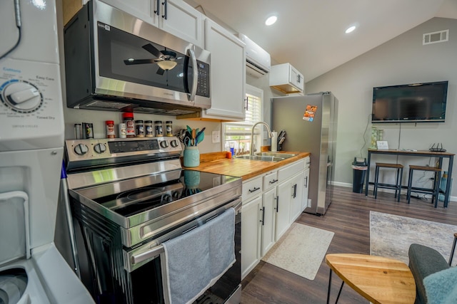 kitchen with visible vents, a sink, vaulted ceiling, white cabinets, and appliances with stainless steel finishes