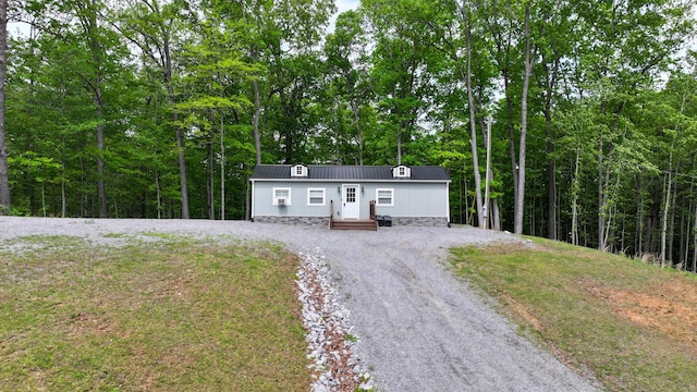 manufactured / mobile home featuring metal roof, a wooded view, and curved driveway