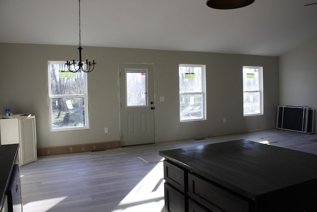 foyer featuring a chandelier, plenty of natural light, light wood-style floors, and baseboards