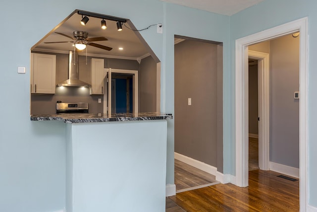 kitchen with dark wood finished floors, visible vents, stainless steel range with electric cooktop, wall chimney range hood, and white cabinets