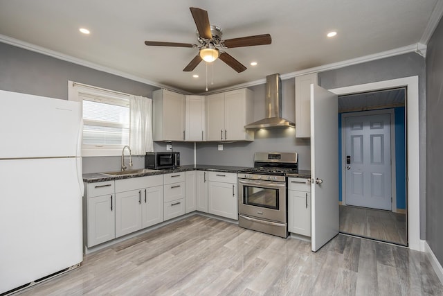 kitchen with freestanding refrigerator, ornamental molding, gas stove, a sink, and wall chimney exhaust hood