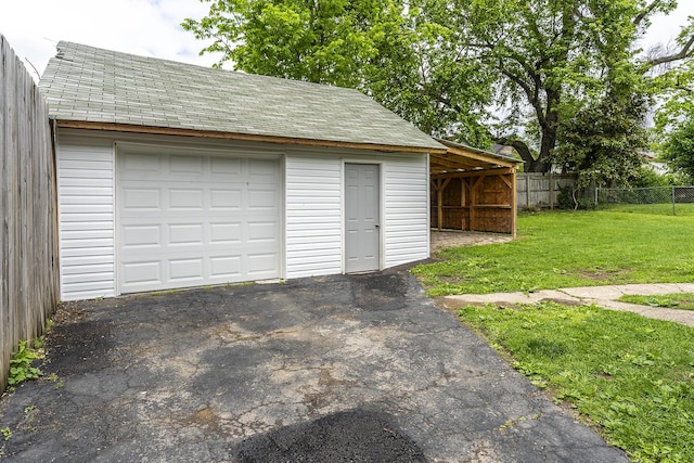 detached garage featuring aphalt driveway and fence