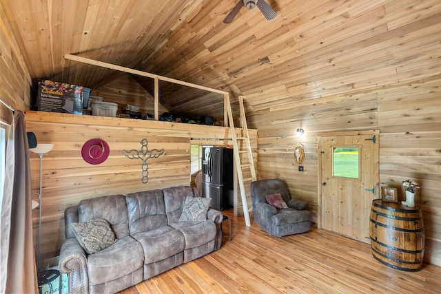 living room featuring wood ceiling, a ceiling fan, wood-type flooring, wooden walls, and vaulted ceiling