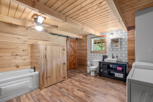 interior space with washer and clothes dryer, wood walls, toilet, beam ceiling, and wooden ceiling