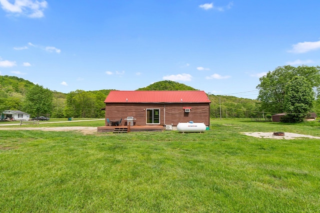 back of house featuring a fire pit, metal roof, a deck, and a lawn