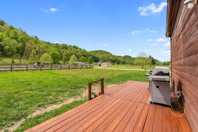 deck featuring fence, a yard, a shed, an outbuilding, and grilling area