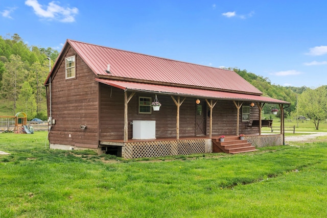 rear view of property featuring a yard, metal roof, and covered porch