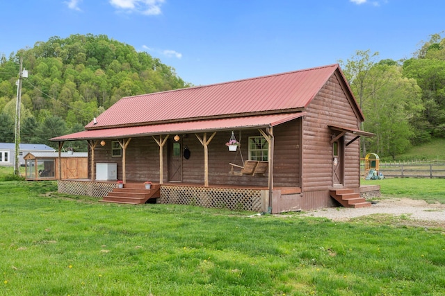 view of front facade featuring covered porch, log veneer siding, fence, metal roof, and a front lawn