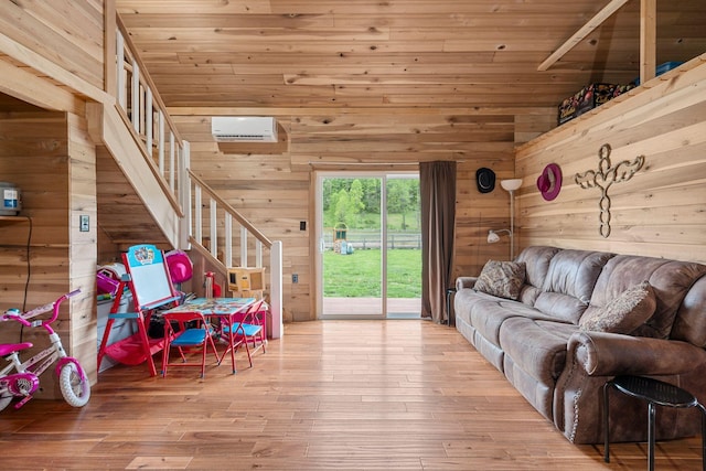 living area with lofted ceiling, stairway, wooden walls, wood-type flooring, and a wall mounted AC
