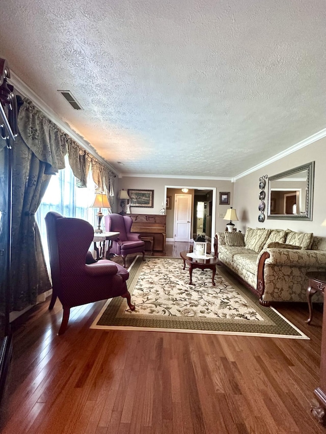 living area featuring a textured ceiling, visible vents, ornamental molding, and hardwood / wood-style flooring