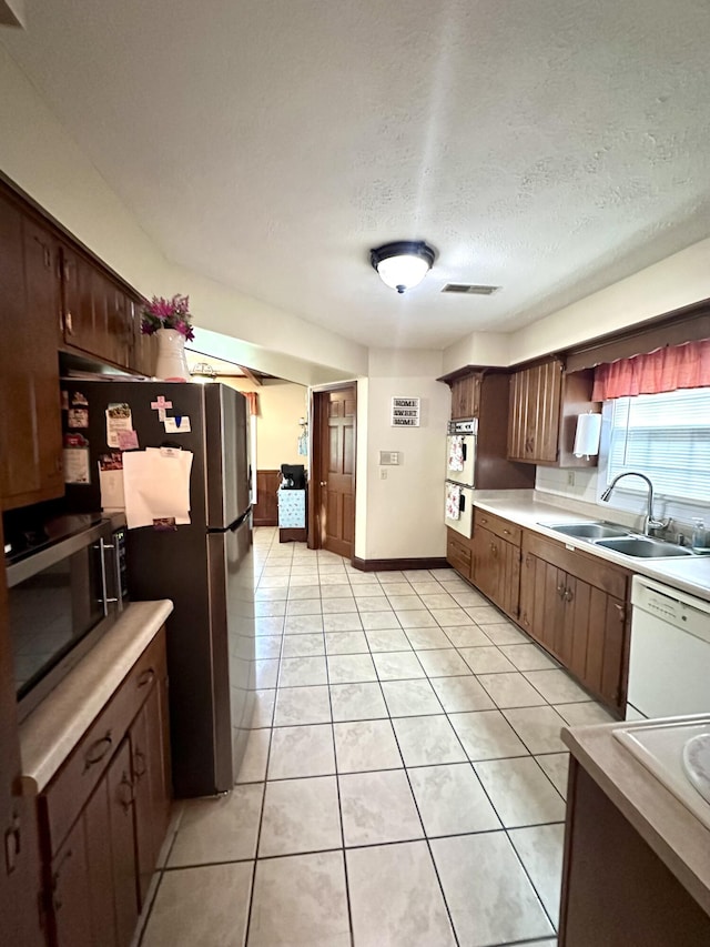 kitchen with a sink, visible vents, light countertops, light tile patterned floors, and appliances with stainless steel finishes