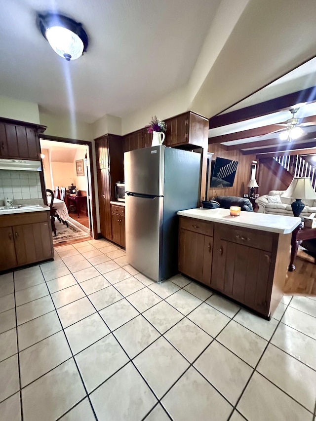 kitchen with freestanding refrigerator, light countertops, light tile patterned floors, and a sink