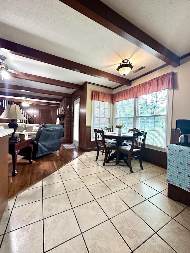 dining space with light tile patterned flooring, a textured ceiling, beamed ceiling, and visible vents
