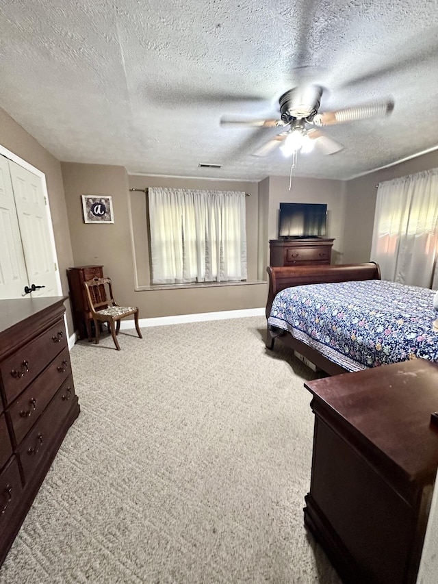 bedroom with a textured ceiling, baseboards, ceiling fan, visible vents, and light colored carpet