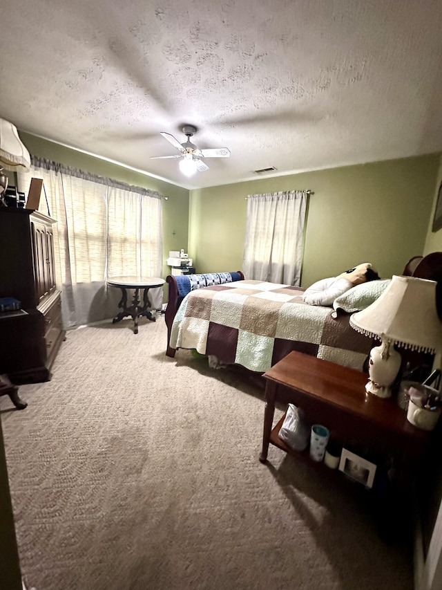 bedroom featuring carpet, a textured ceiling, visible vents, and ceiling fan