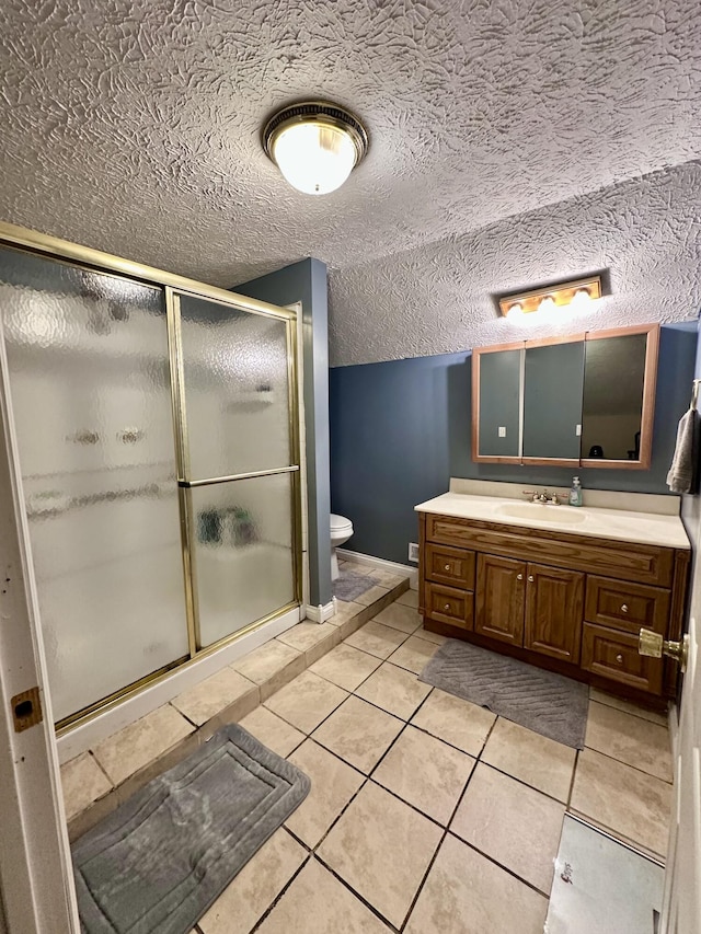 bathroom featuring toilet, vanity, tile patterned floors, a shower stall, and baseboards