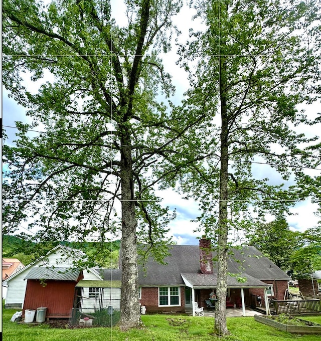 rear view of property with fence, a chimney, a lawn, brick siding, and a patio area