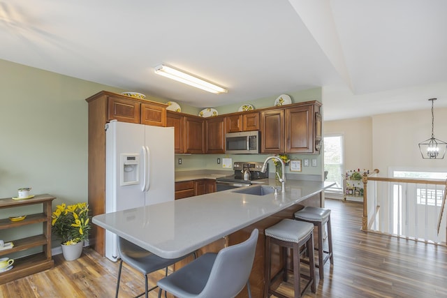 1208 Four Wynds Trl, Lexington, KY 40515 - kitchen featuring appliances with stainless steel finishes, a sink, a peninsula, a breakfast bar, and wood finished floors
