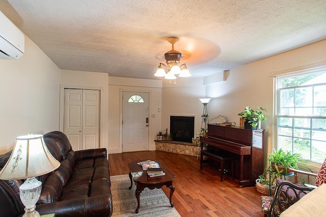121 Meredith Ave, Frankfort, KY 40601 - living room featuring an AC wall unit, wood finished floors, a fireplace with raised hearth, a textured ceiling, and a ceiling fan