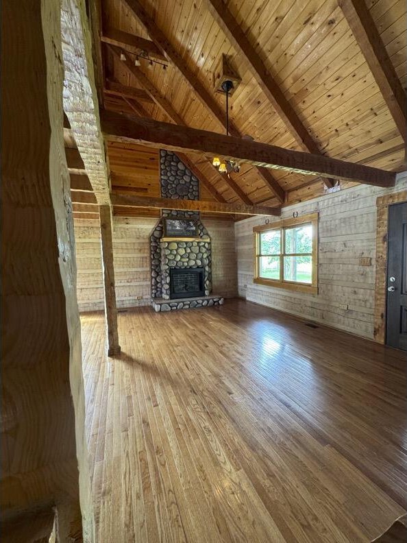 792 Tuggle Rd, Lancaster, KY 40444 - unfurnished living room with wooden ceiling, hardwood / wood-style flooring, beamed ceiling, a fireplace, and wooden walls