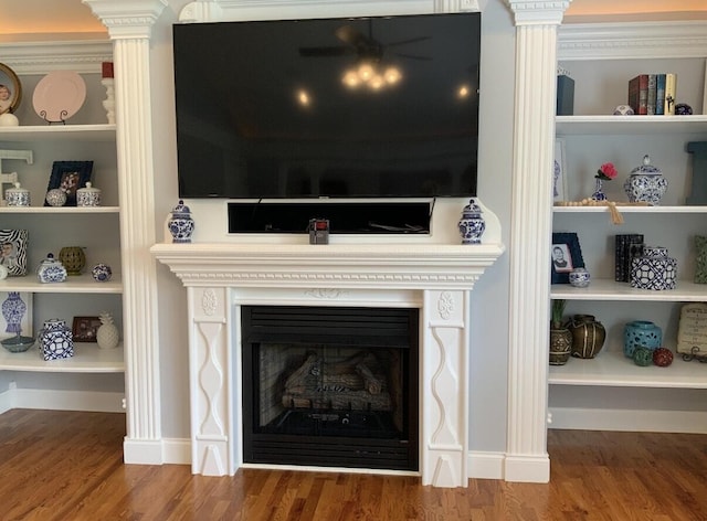 interior details with wood finished floors, a fireplace, and ornate columns