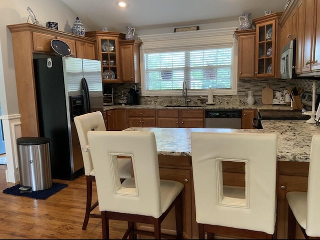 kitchen featuring a peninsula, appliances with stainless steel finishes, brown cabinets, and a sink