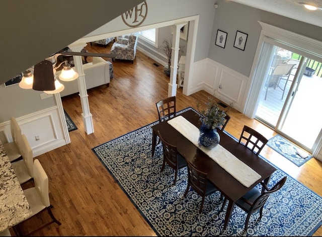 dining area with a wealth of natural light, a decorative wall, wainscoting, and light wood-style flooring