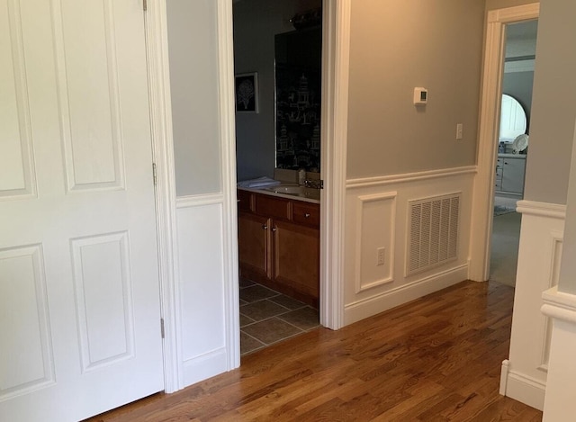 corridor featuring visible vents, wood finished floors, and a sink